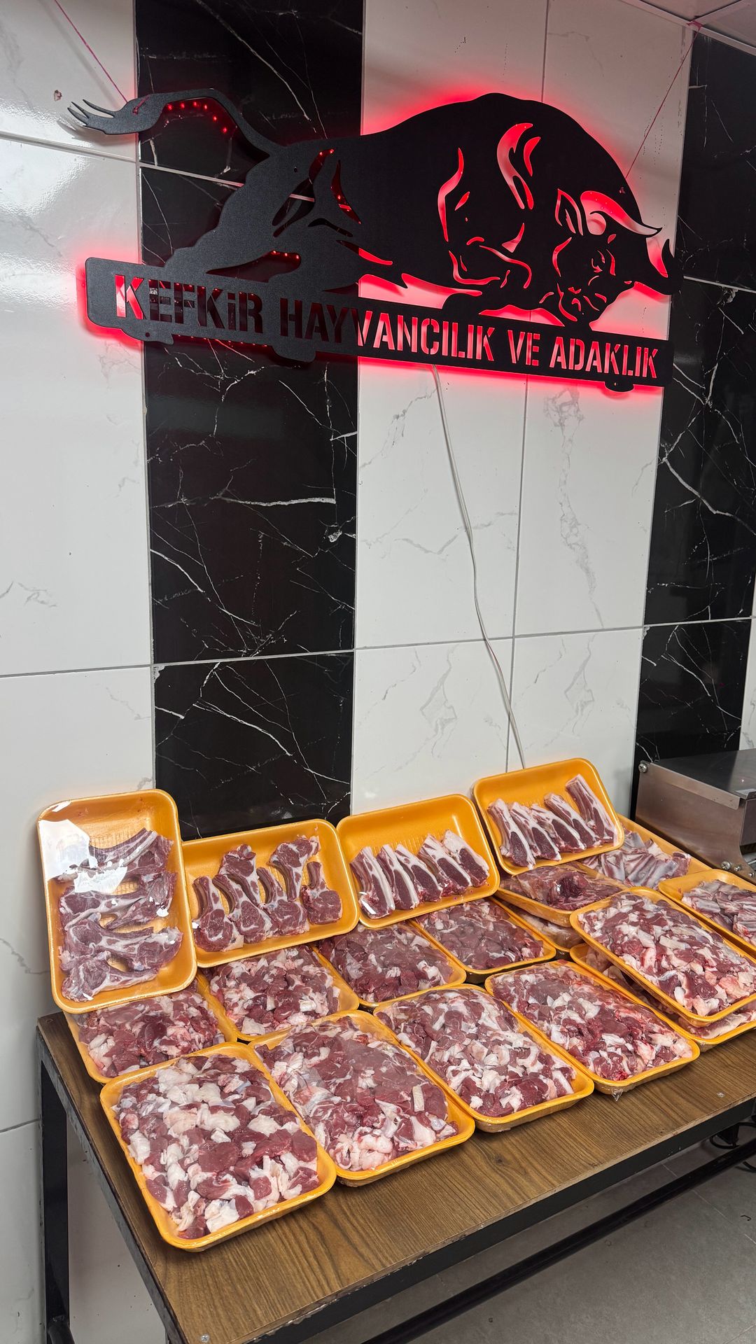 Kefkir Hayvancılık ve Adaklık tesisinde ışıklı boğa tabelası ve tabaklara paylanmış etler